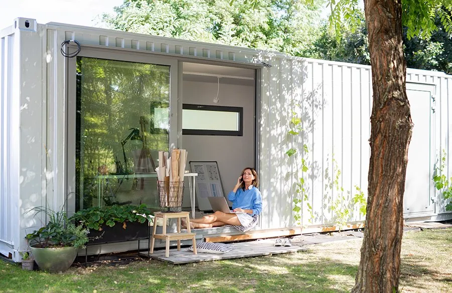 Converted container office with sliding glass frontage, in use as a garden workspace
