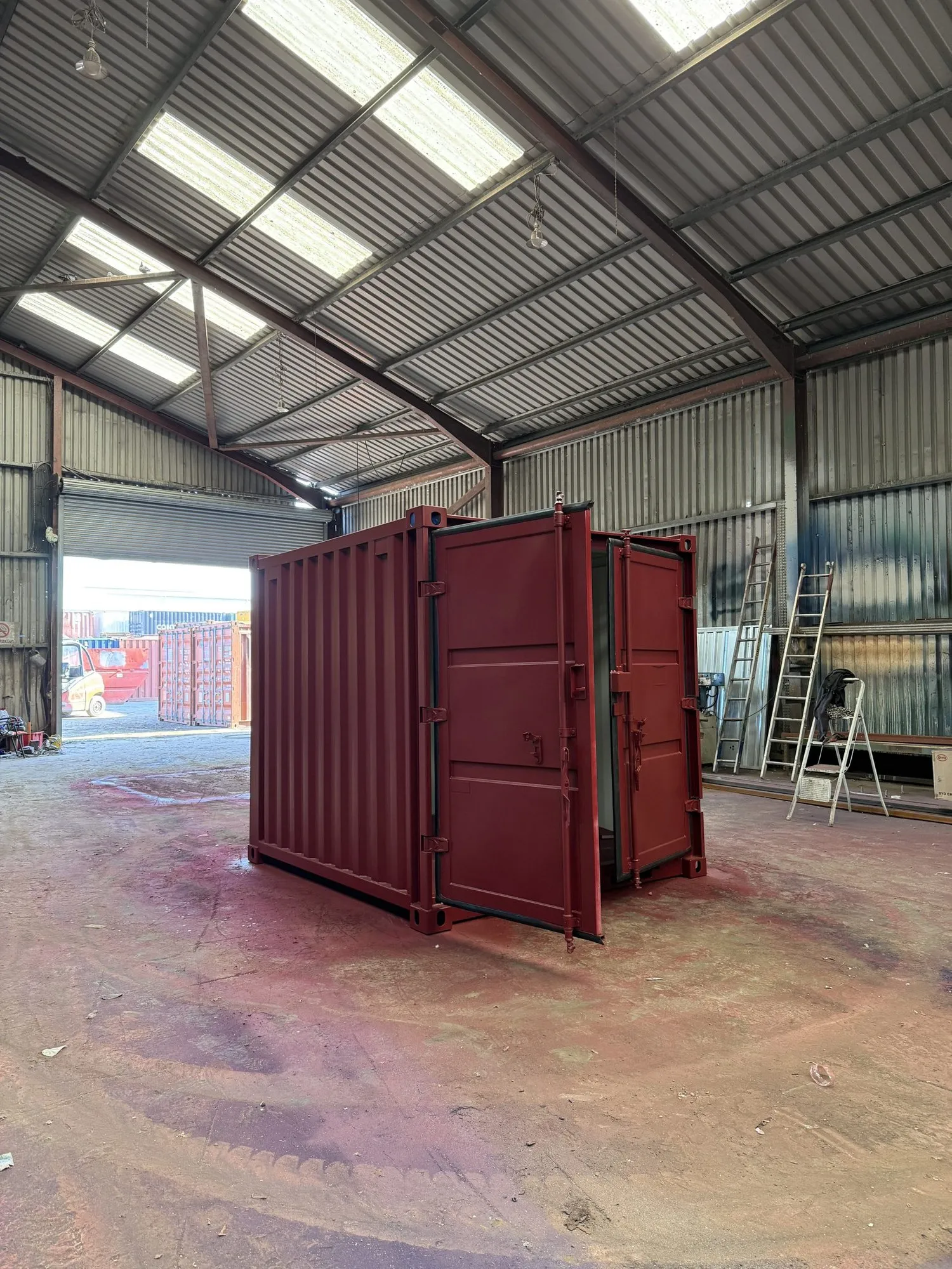Shipping container spray-painted in a deep berry brand colour at the Container Care workshop