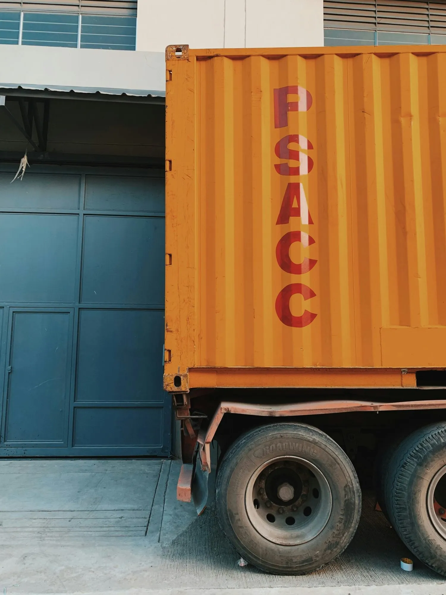 Shipping container arriving by lorry outside a warehouse